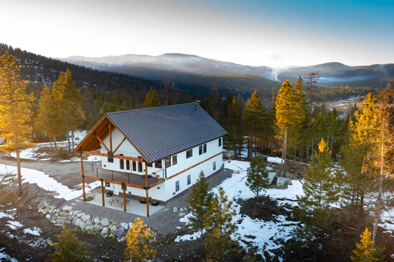 A Built Right timber-frame home above Kalispell at golden hour, larch and pine around it and the valley beyond